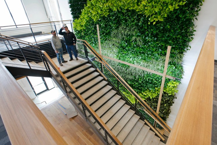 Woodworkers Bruce King, left, and Tracy Chadbourne discuss work in the University of New England's new Danielle N. Ripich Commons last year. The university announced that it is freezing its employees' pay levels to help keep tuition in line after a period of expansion. 