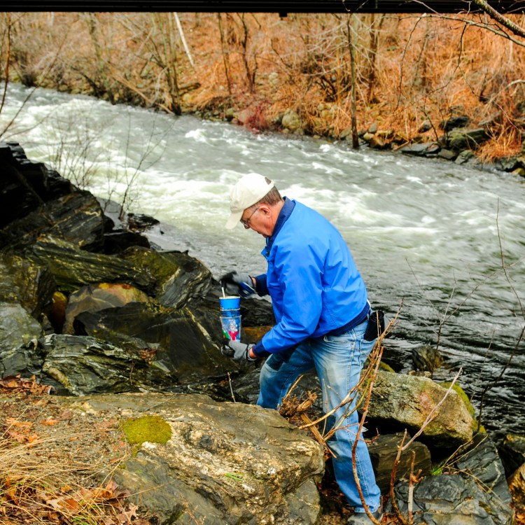 Bob Simpson picks up trash along the banks of Cobbosseecontee Stream in Gardiner. He was part of a group doing the cleanup for Earth Day.