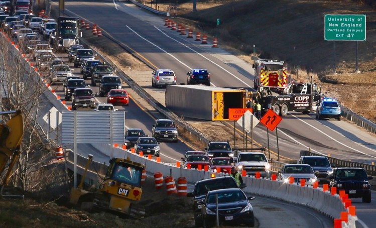 The tractor-trailer that crashed early Friday morning lies on its side in the northbound lanes of the Maine Turnpike in Portland.
