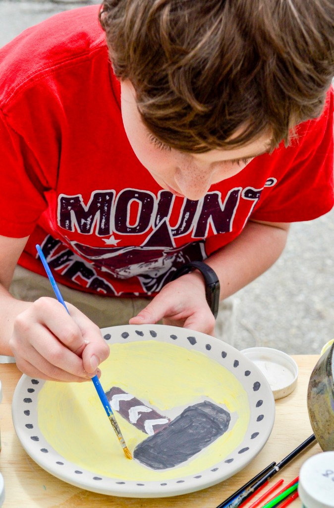 Eddie Schmidt, 11, of Chelsea, paints Thor's hammer onto a plate Saturday during a Maine Pottery Tour event at Fine Mess Pottery in Augusta. 