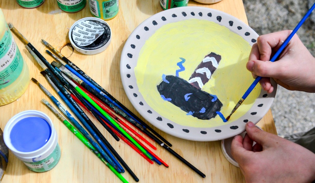 Eddie Schmidt, 11, of Chelsea, paints Thor's hammer onto a plate Saturday during a Maine Pottery Tour event at Fine Mess Pottery in Augusta. 
