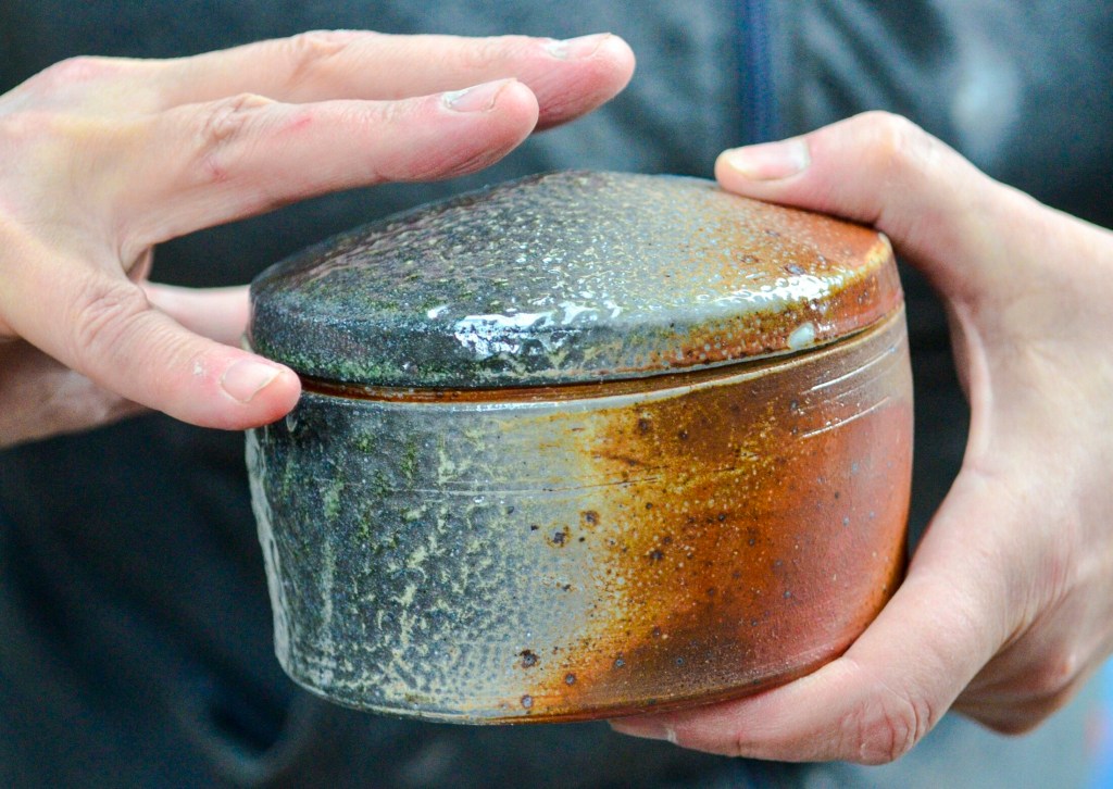 Lori Watts talks about how the soda firing method gives the two-tone colors to a piece just taken out of kiln Saturday during a Maine Pottery Tour event at Fine Mess Pottery in Augusta. Soda firing is a type of stoneware firing wherein soda ash and baking soda are introduced to the flame. The intense heat in the kiln splits the sodium and carbon, which flies around in the firing chamber and onto the pots. The sodium interacts with the silica and calcium carbonate in the pottery — as well any glazes that have been applied — to form a layer of glass.