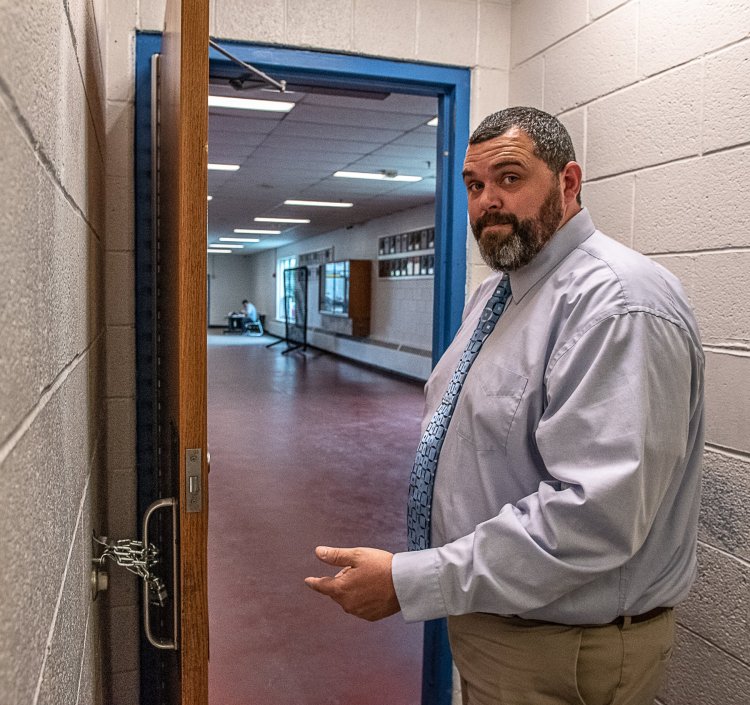 Jake Langlais, principal of Lewiston High School, shows the lock and chain holding a bathroom door open. Langlais says open bathroom doors decrease incidents of bullying, smoking and other acts.