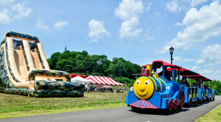 People ride a train past a slide as they tour around Mill Park on June 30, 2018, during the Kennebec River Day Augusta. 