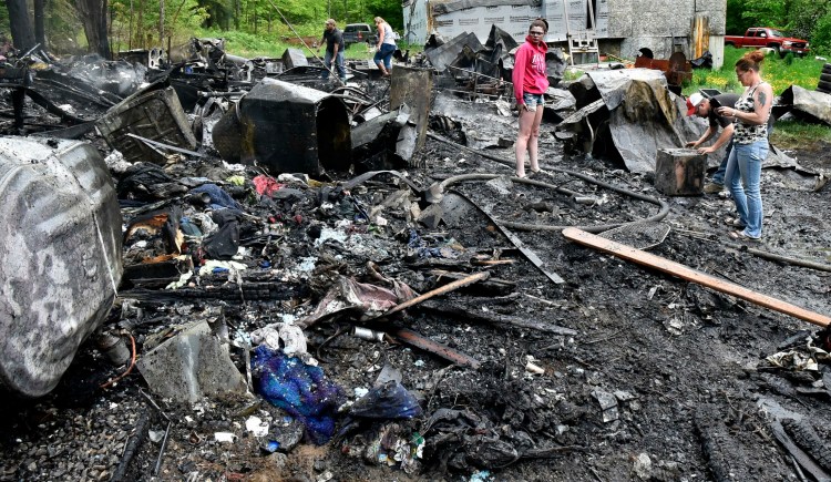 Deborah Ashby, right, and her son Glenn Nickerson examine a charred safe that was among the ruins of her mobile home that was destroyed by fire on Kimball Lane in Starks on Monday.