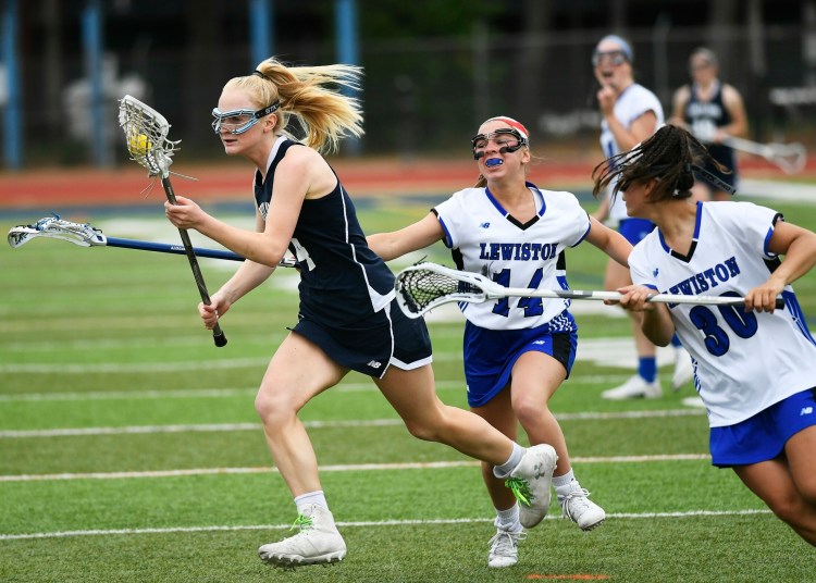 Portland's Annika Moore runs with the ball as she tries to elude Lewiston's Melina Masseli and Paige Pomerleau.