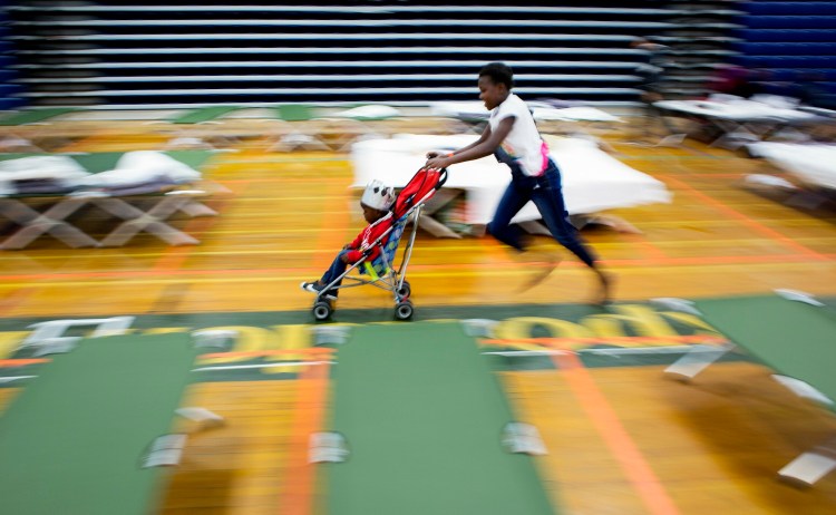 Alegria Landu, 9, pushes her brother Gabriel, 3, in a stroller at an emergency shelter for asylum seekers at the Portland Expo on Thursday.