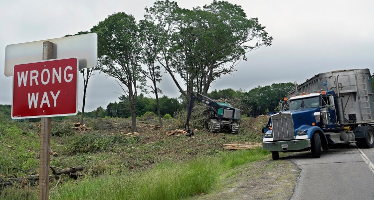 Loggers chip wood felled at Exit 112A Thursday in Augusta off Interstate 95. The Maine DOT recently clear cut and stumped all the trees between the exit and on ramps at 112B.