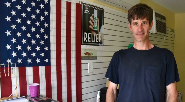 Nathan White stands in the lobby of his medical marijuana shop on Tuesday in China. Town officials have apologized to White for suggesting he was selling recreational marijuana instead of medical products.