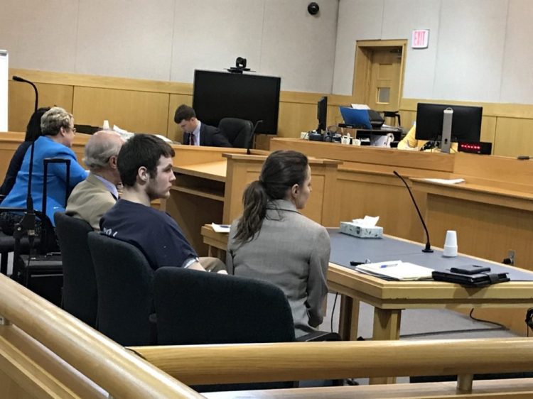 Dominic Sylvester, center, appears in West Bath District Court with his attorneys. He’s charged with depraved indifference murder in the 2018 death of his grandmother.