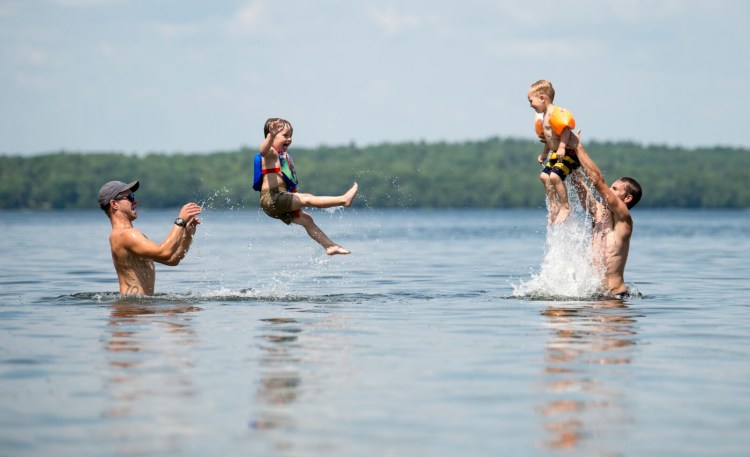 Cory Gooldrup, left, tosses his son Ayden, 3, as his Cory Gooldrup's brother, AJ Gooldrup, right, throws his own son, Noah Gooldrup, 3, as they escape from the heat Saturday in East Pond in Oakland.