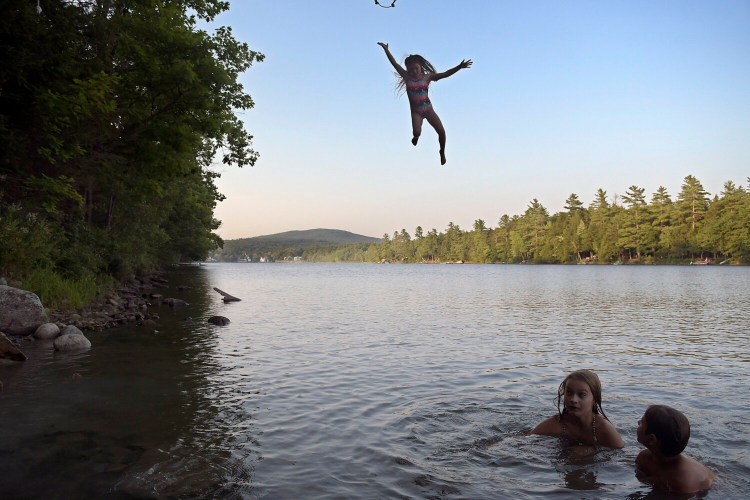 A girl drops in on her friends after releasing from a rope swing Tuesday on Minnehonk Lake in Mount Vernon. A crew of seven children brought their parents for the daily dip on the lake in their hometown. The temperature reached into the 90s and is forecasted to remain high with humidity throughout the week, according to the National Weather Service. 