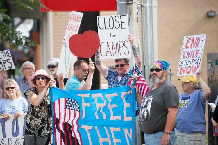 Jasmine Violette, of Albion, left, and Matthew Crane, right, hold a giant sign Friday in protest of immigration detention and family separation on the southern border on the corner of Temple and Main Streets in Waterville.