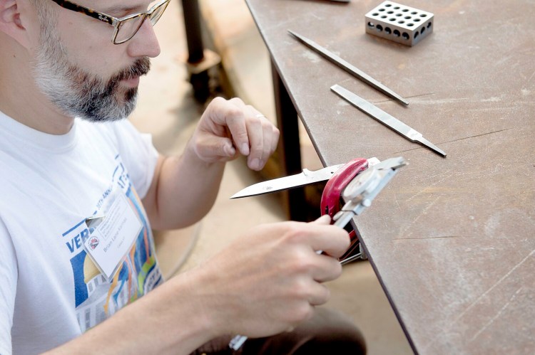 Brian Lane-Karnas of Calais, Vt., works on a knife Saturday at the symposium in Auburn. 