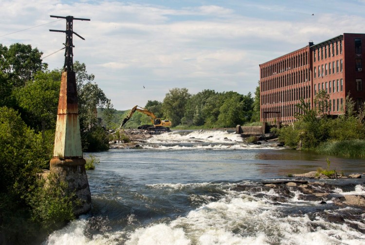 A crew begins work Tuesday to remove the Saccarappa Falls dam near Bridge Street in Westbrook. The dam's removal is a part of a settlement between the Sappi paper company and conservation groups.