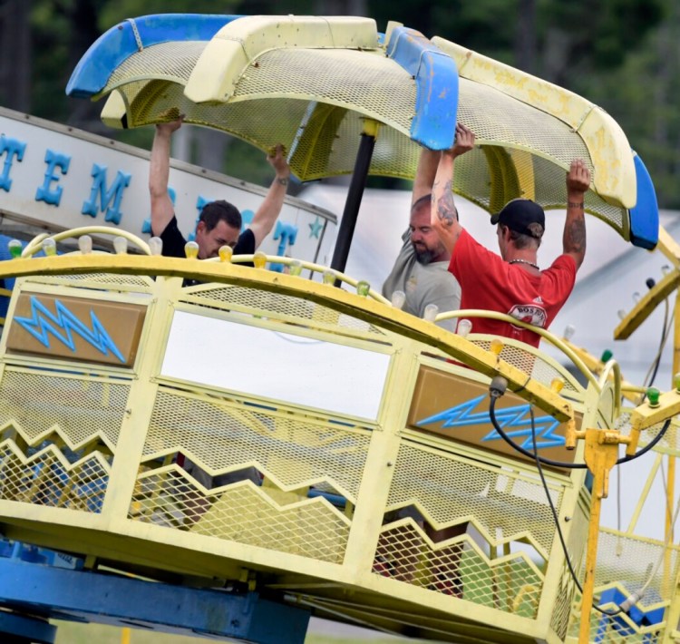 Workers with Kavanaugh Amusements assemble a ride Tuesday on the midway in preparation for the Pittston Fair.