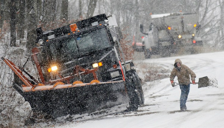 Jake Laughlin tosses sand onto Maple Street in Farmingdale on Dec. 5, 2016, as a colleague prepares to descend the snow covered road with a plow truck. 