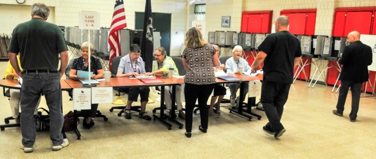 Voters pick up ballots for the school budget special election just after polls opened Tuesday at 8 a.m. at the Winthrop Town Office.