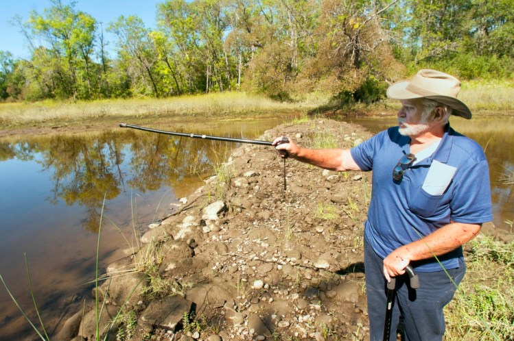 Jim Lothridge, chairman of the Kennebec River Walk committee, stands on a causeway that almost connects the mainland to Bodge Sands Island, in background, on Saturday in Pittston.