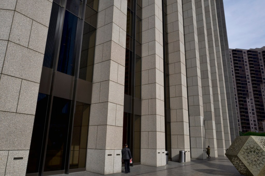 FILE - In this Jan. 8, 2019, file photo people are towered by the front facade of the Bank of America Plaza Building in downtown Los Angeles. The shareholder comes first has for years been the mantra of the Business Roundtable, a group representing the most powerful CEOs in America. The group on Monday, Aug. 19, released a new mission statement that implies a foundational shift; a step back from shareholder primacy. (AP Photo/Richard Vogel, File)