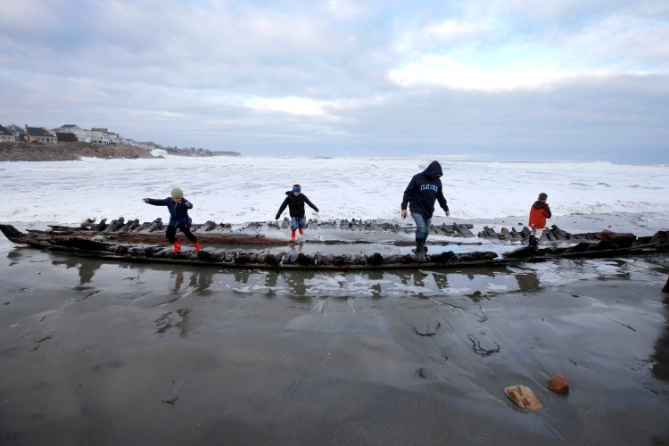 YORK, ME - MARCH 6: A group of people climbs on the skeleton of a shipwrecked sloop at Short Sands Beach in March 2019. The wreck emerged from the sand during a heavy surf, as it does from time to time. 