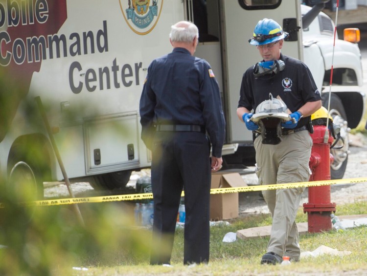 Fire Marshal investigator Larry Moral carries Fire Capt. Michael Bell's helmet to Stephan Bunker of the Farmington Fire Department. The helmet was found in the rubble from the explosion at the LEAP Inc. building. Bell, 68, was killed in the propane explosion.