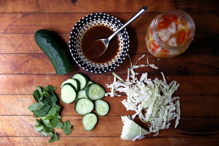 Mise en place for Owen's Vietnamese Chicken and Rice Bowl: cucumber slices; marinade; pickled kohlrabi, daikon radish, carrot and red chili pepper; sliced cabbage; and mixed fresh basil, mint and cilantro. 