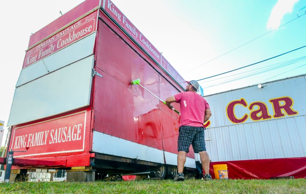 Jared Goodwin scrubs down the King Family Cookhouse trailer Tuesday at the Litchfield Fairgrounds. He'd just moved the family's summer business from the Windsor Fair where they'd worked the previous week.