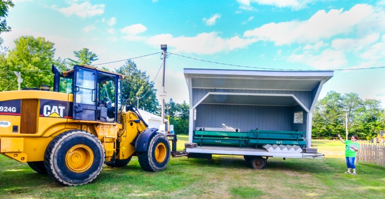 Chuck Snyder, in the loader, maneuvers a stage into position Tuesday while Barbara Moody directs him. Volunteers have been preparing for the Litchfield Fair, which runs from Friday through Sunday.