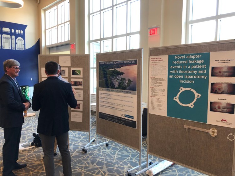 Attendees at the Maine Center for Entrepreneurs Life Science Ventures Seminar on Friday in Portland chat while standing next to a series of informational posters. The seminar's purpose was to discuss ways to grow Maine's biosciences industry.