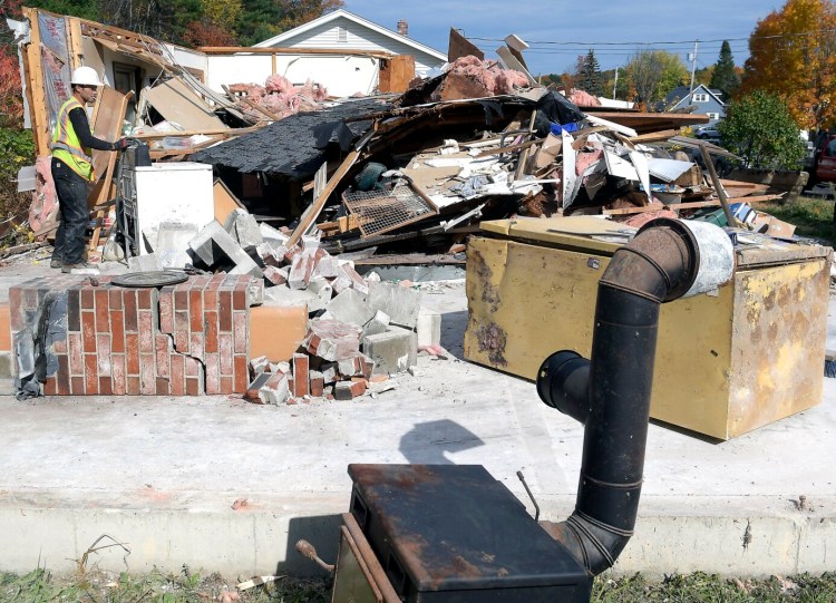 A worker razes the home at 68 Windy St. Tuesday in Augusta.