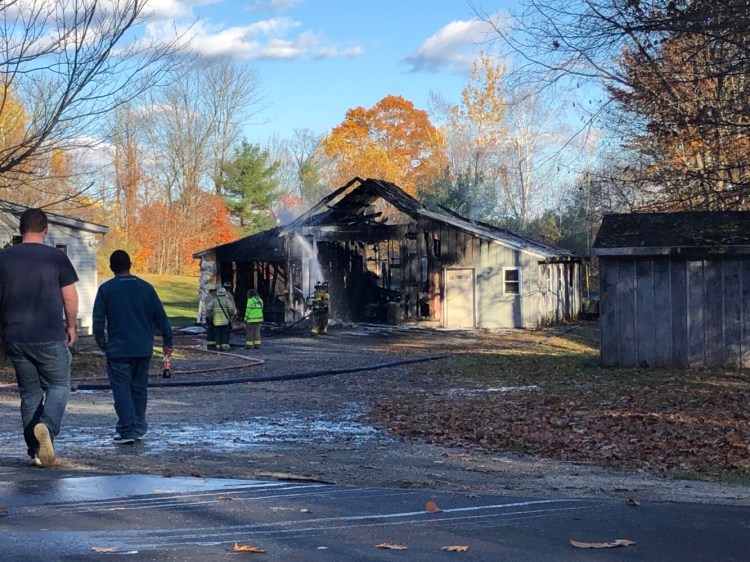 Firefighters continue to attack hot spots Saturday at a garage fire on South Monmouth Road in Monmouth. 