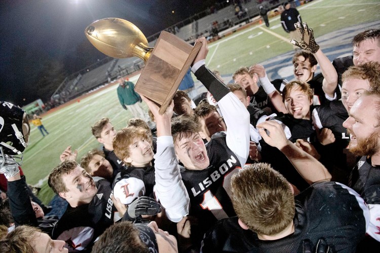 Lisbon/St. Dominic quarterback Seth Leeman hoists the Gold Ball after the Greyhounds beat Bucksport 38-8 to win the Class D state championship on Saturday at Fitzpatrick Stadium in Portland.