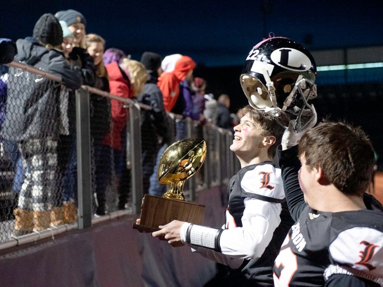 Lisbon/St. Dominic quarterback Seth Leeman shows the crowd the Gold Ball after the Greyhounds beat Bucksport 28-8 to win the Class D title on Saturday at Fitzpatrick Stadium in Portland.