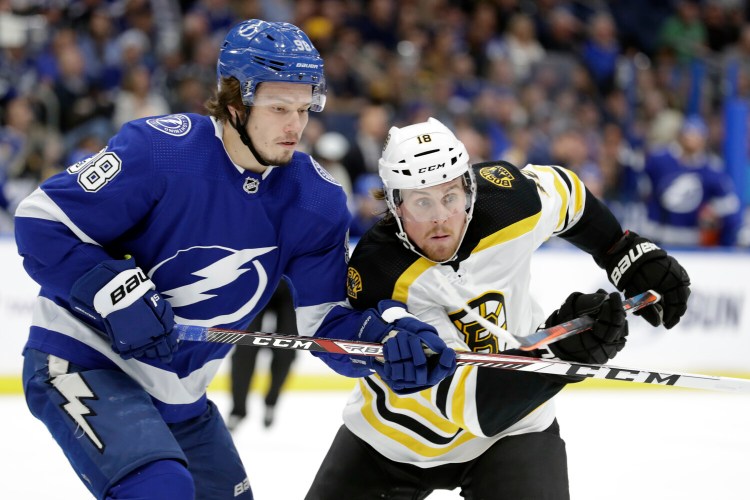 Tampa Bay defenseman Mikhail Sergachev, left, ties up Boston right wing Brett Ritchie during Thursday's game in Tampa, Fla. 