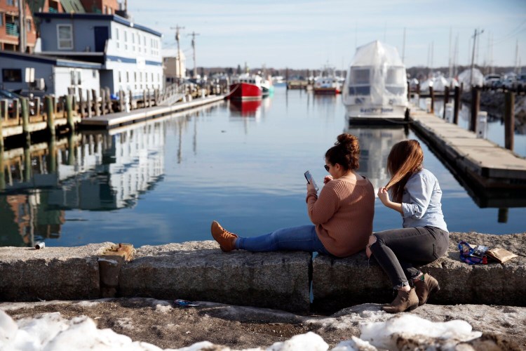 PORTLAND, ME - FEBRUARY 21: University of Southern Maine students Jordanna Ford, left, and Delaney O'Connor take in the unseasonably warm weather on the Old Port waterfront adajcent to Portland Pier. (Staff photo by Ben McCanna/Staff Photographer)