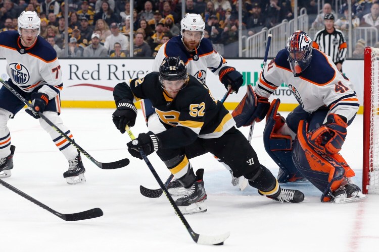 Boston's Sean Kuraly, front, tries to control the puck in front of Edmonton goalie Mike Smith during Saturday's game in Boston.