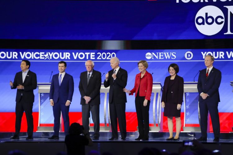 From left, Democratic presidential candidates entrepreneur Andrew Yang, former South Bend Mayor Pete Buttigieg, Sen. Bernie Sanders, I-Vt., former Vice President Joe Biden, Sen. Elizabeth Warren, D-Mass., Sen. Amy Klobuchar, D-Minn., and businessman Tom Steyer stand on stage Friday before the start of a primary debate hosted by ABC News, Apple News and WMUR-TV at Saint Anselm College in Manchester, N.H.