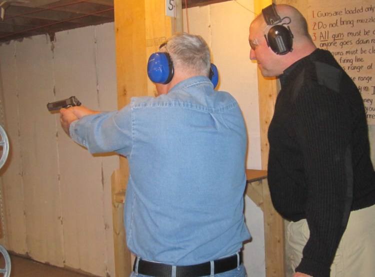 Sheriff Scott Nichols, right, gives basic hand gun instructions to a student.
