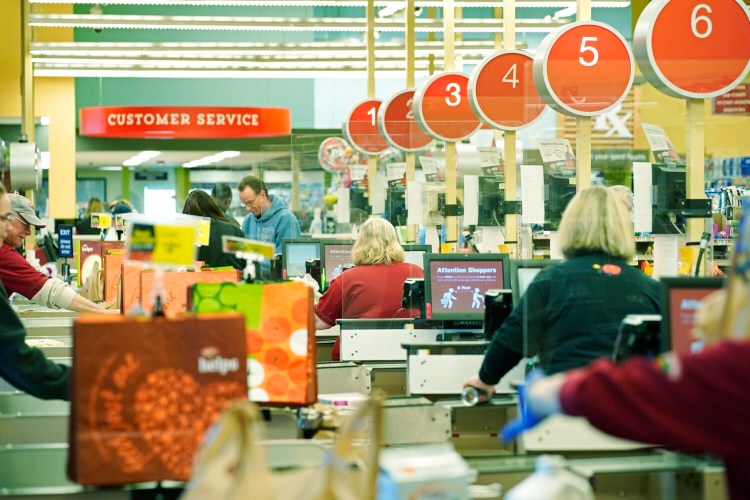 Cashiers ring up customers at the Hannaford supermarket in Scarborough on March 27. Hannaford stores have installed Plexiglas barriers at the cash registers as a safety precaution for cashiers and customers during the coronavirus outbreak. 