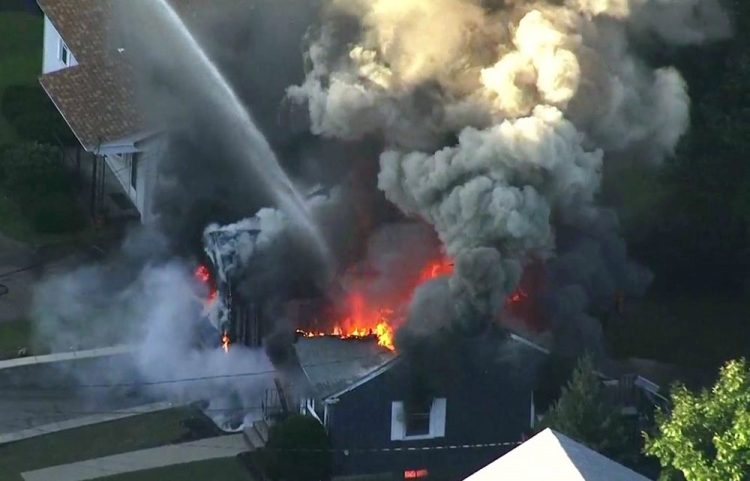 Flames consume the roof of a home following an explosion Sept. 13, 2018, in Lawrence, Mass. The U.S. Attorney's office in Boston announced Wednesday that Columbia Gas Columbia agreed to plead guilty to violating the Pipeline Safety Act following an investigation into the catastrophic gas explosions.