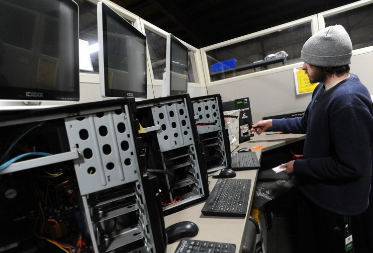 Clayton Martin works April 21 in the data security department of the Waterville facility of a nonprofit known as Give IT. Get IT. Martin is replacing hard drives in the desktop stations at the left  as computers are refurbished for reuse. The company refurbishes computers for low-income families, students and others.