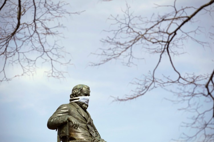 The statue of Henry Wadsworth Longfellow at Longfellow Square in Portland is adorned with a protective mask Monday.