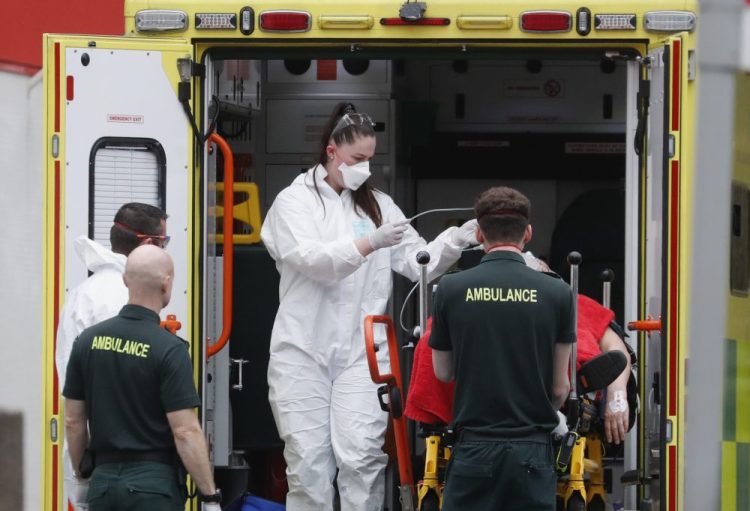 Medical workers wearing equipment to protect themselves from the coronavirus bring a patient to St. Thomas' Hospital in Westminster in London on Monday.