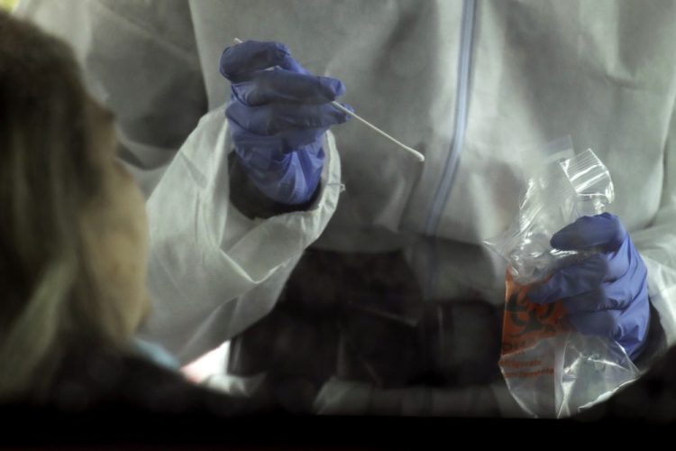 A nurse prepares to take a sample for a COVID-19 test during a drive-in testing outreach in the parking lot of a church April 22 in Kansas City, Mo.