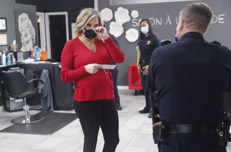 Salon owner Shelley Luther holds a citation and speaks with a Dallas police officer after she was cited for reopening her Salon A la Mode in Dallas last month. She continued to defy the order and stayed open despite restrictions in force at the time. A judge on Tuesday said he would consider levying a fine instead of jail time if Luther apologized, but she told the judge, "I am not going to shut the salon." 