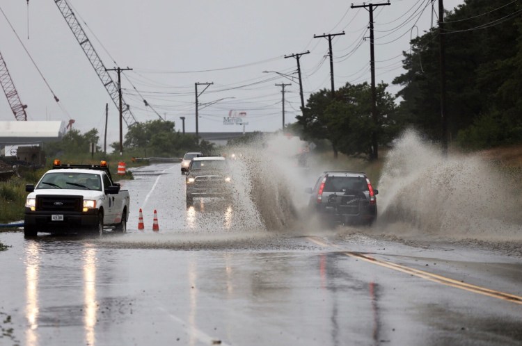 A vehicle plows through a flooded section of Commercial Street in Portland on Monday. 