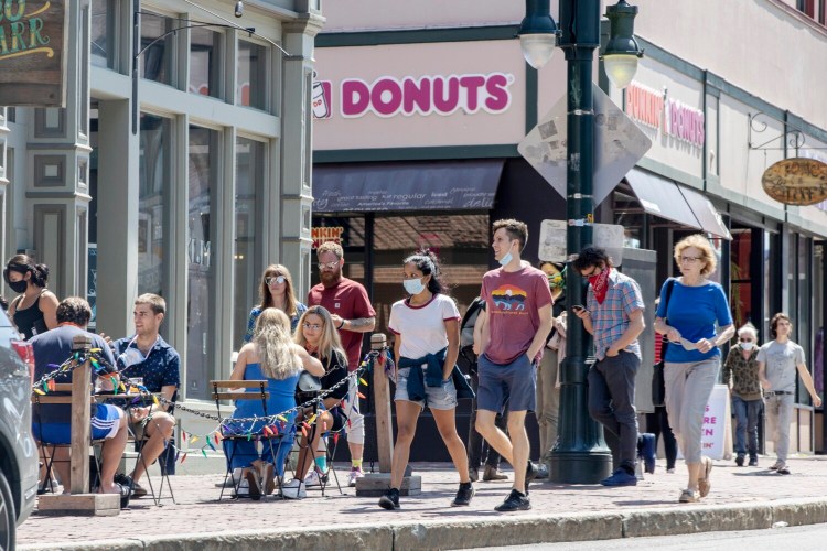 Pedestrians pass by people eating outside Taco Escobar on Congress Street in downtown Portland on Saturday.