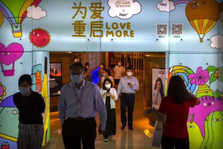 People wearing face masks to protect against the coronavirus walk through a shopping mall in Beijing on Aug. 14. Today's guest columinst writes: " ... COVID-19 has shown us that our world is connected more than ever by transportation and technology, so we must work with each other better than ever. ..." 