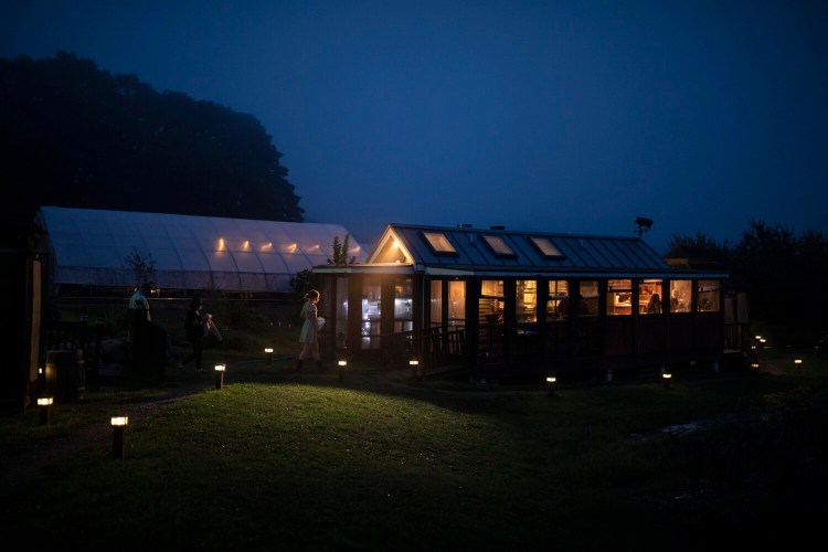 Hostess Claire Merrill leads diners to their table in the attached porch at The Well at Jordan’s Farm, A seasonal restaurant with diners eating outdoors in separate gazebo or at picnic tables, The Well seems almost perfectly designed to face the coronavirus pandemic.